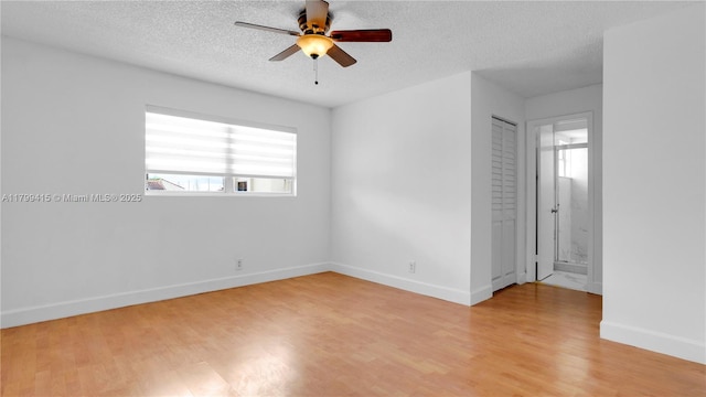 unfurnished bedroom with light wood finished floors, a textured ceiling, baseboards, ensuite bath, and ceiling fan