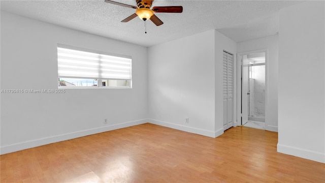 spare room featuring ceiling fan, a textured ceiling, light wood-type flooring, and baseboards