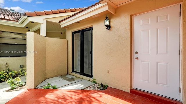 property entrance featuring stucco siding, a patio, and a tiled roof