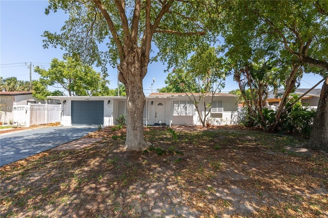 ranch-style house with a garage, concrete driveway, and fence