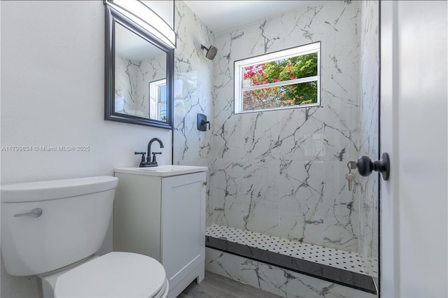 bathroom featuring a marble finish shower, vanity, and toilet