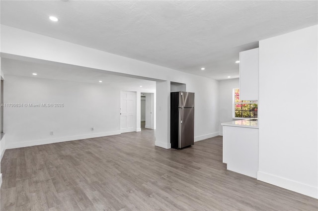 unfurnished living room featuring wood finished floors, recessed lighting, and baseboards