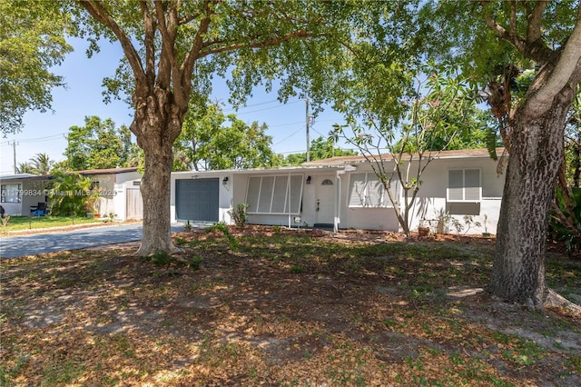 single story home featuring asphalt driveway, an attached garage, and stucco siding