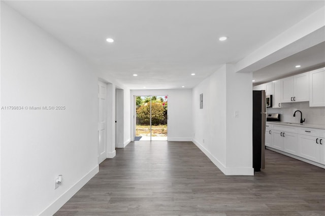 kitchen with a sink, recessed lighting, baseboards, white cabinetry, and light countertops