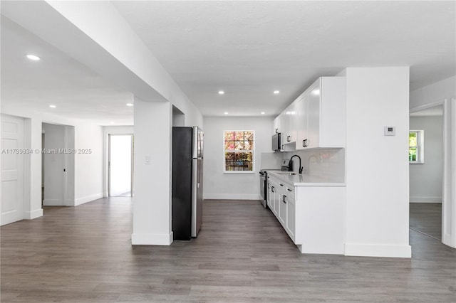 kitchen featuring appliances with stainless steel finishes, light countertops, baseboards, wood finished floors, and white cabinets