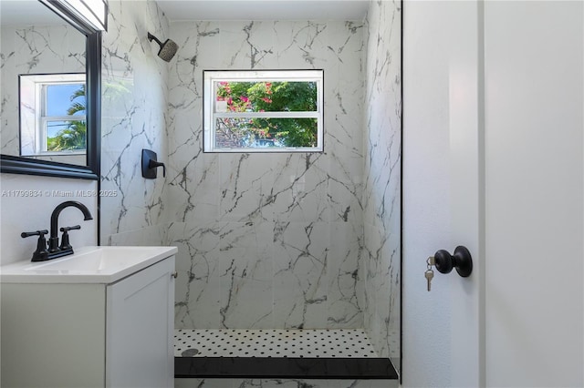 full bath featuring a marble finish shower, healthy amount of natural light, and vanity