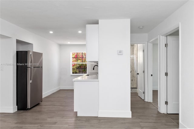 hallway with baseboards, light wood-style flooring, recessed lighting, and a sink