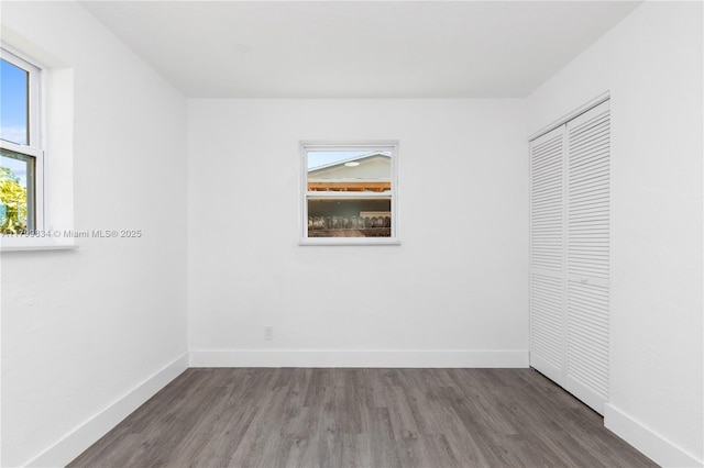 unfurnished bedroom featuring wood finished floors, baseboards, and a closet