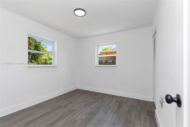 empty room with dark wood finished floors and baseboards