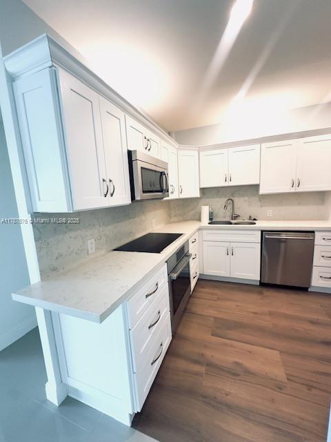 4200 Hillcrest Dr Unit 1017, Hollywood, FL 33021 - kitchen featuring appliances with stainless steel finishes, a sink, decorative backsplash, white cabinets, and dark wood-style flooring