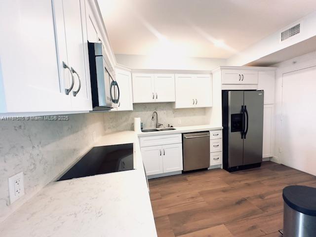 4200 Hillcrest Dr Unit 1017, Hollywood, FL 33021 - kitchen featuring stainless steel appliances, a sink, white cabinets, light countertops, and dark wood-type flooring