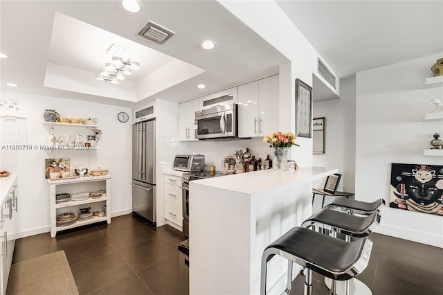 1700 NE 105th St Unit 108, Miami Shores, FL 33138 - kitchen featuring appliances with stainless steel finishes, a breakfast bar, white cabinetry, a peninsula, and light countertops