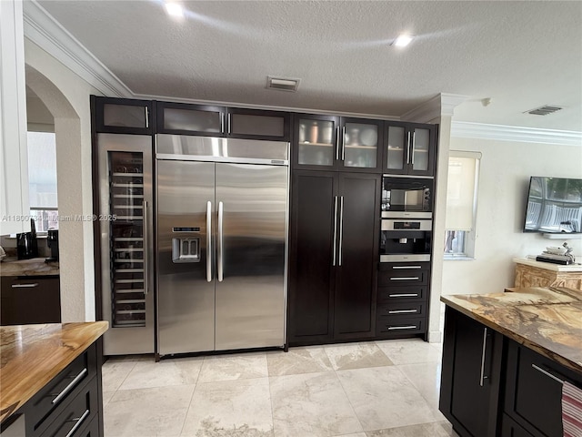8389 NW 115th Ct, Doral, FL 33178 - kitchen with built in appliances, butcher block countertops, crown molding, arched walkways, and glass insert cabinets