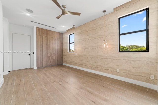 spare room featuring a ceiling fan, light wood-style floors, and baseboards
