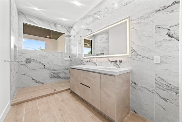 full bathroom featuring a marble finish shower, tile walls, and double vanity