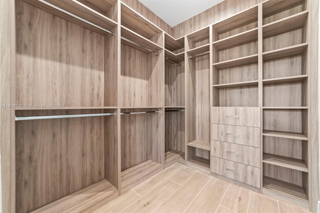 walk in closet with elevator and wood finished floors