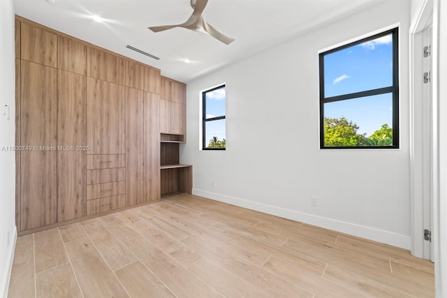empty room featuring healthy amount of natural light, baseboards, light wood-style flooring, and ceiling fan