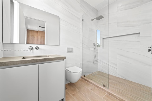 full bath featuring a tile shower, vanity, and toilet