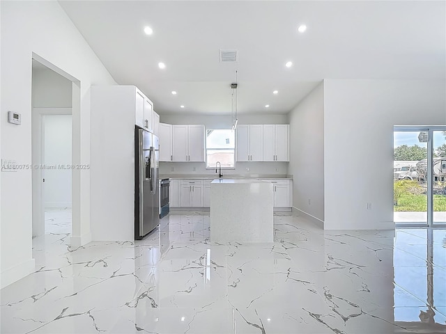 kitchen with stainless steel fridge with ice dispenser, recessed lighting, light marble finish floors, a sink, and light countertops