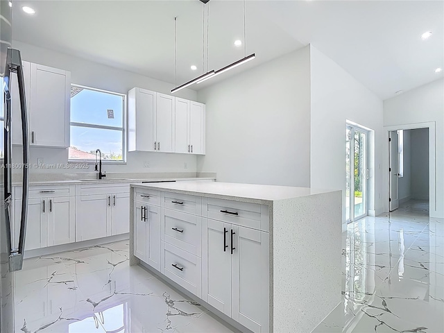 kitchen with a sink, light marble finish floors, recessed lighting, white cabinets, and a kitchen island