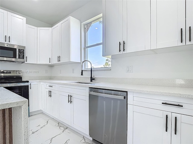 kitchen with stainless steel appliances, a sink, light marble finish flooring, and white cabinetry