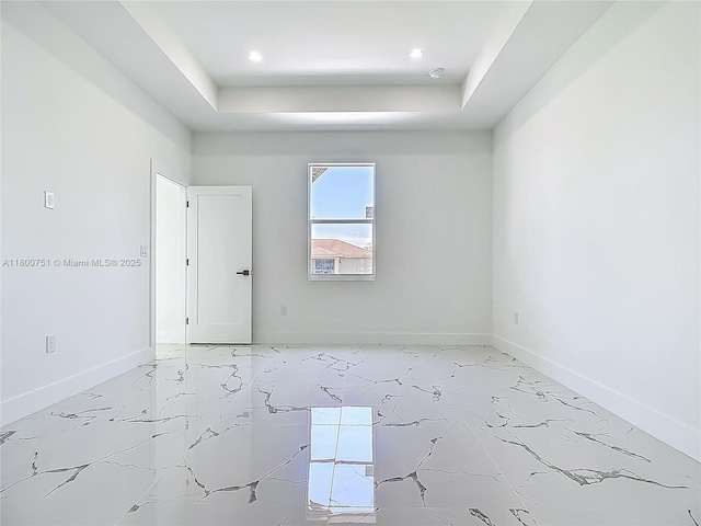 spare room featuring baseboards, a raised ceiling, light marble finish floors, and recessed lighting