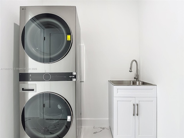 laundry room featuring stacked washer / drying machine, cabinet space, light marble finish floors, and baseboards