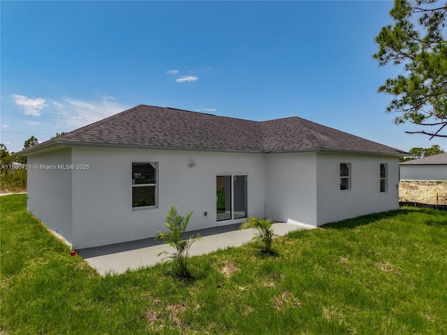 back of house with a shingled roof, stucco siding, and a lawn