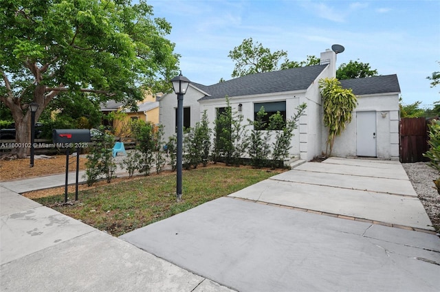 534 NW 50th St, Miami, FL 33127 - view of front of house featuring driveway, stucco siding, a shingled roof, and fence