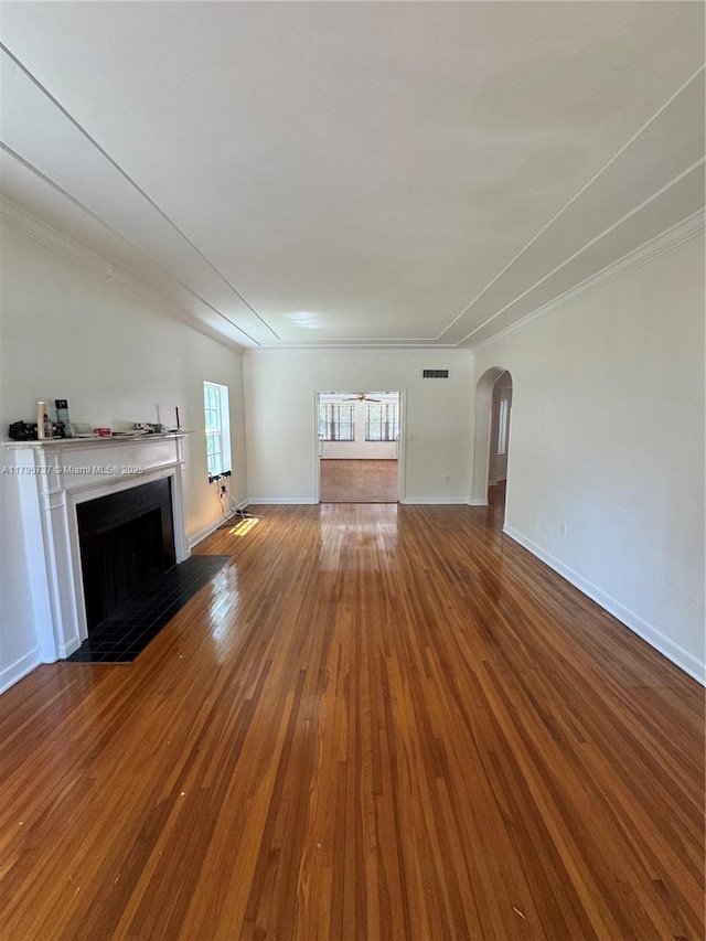 1234 NE 96th St, Miami Shores, FL 33138 - unfurnished living room featuring wood-type flooring, a fireplace with flush hearth, baseboards, arched walkways, and ornamental molding