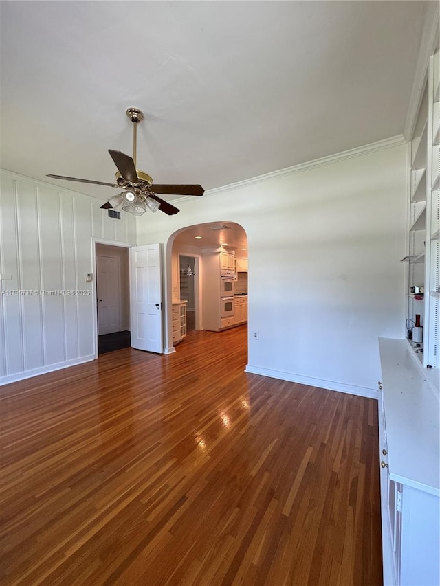 1234 NE 96th St, Miami Shores, FL 33138 - unfurnished living room featuring a ceiling fan, dark wood-type flooring, arched walkways, baseboards, and ornamental molding