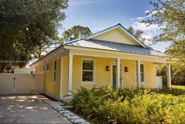 view of front of property featuring a gate, a porch, metal roof, and a standing seam roof