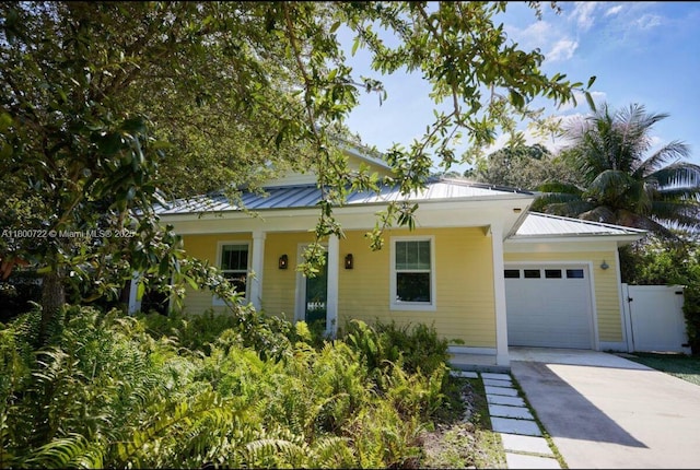 view of front of house featuring an attached garage, concrete driveway, a porch, and metal roof