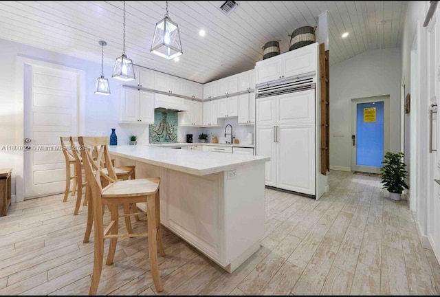 kitchen featuring paneled fridge, wood ceiling, a sink, light wood finished floors, and white cabinets