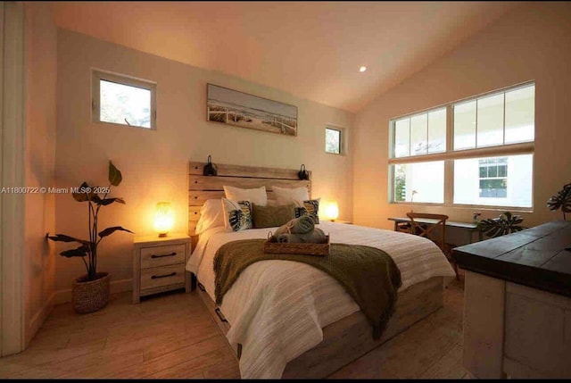 bedroom with multiple windows, lofted ceiling, and light wood-style floors