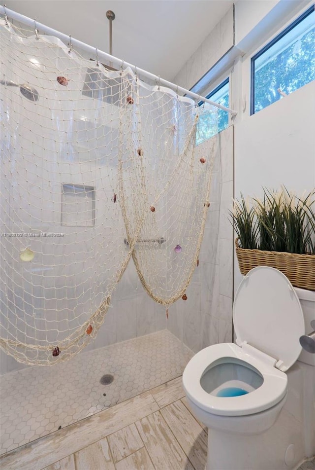 bathroom with tiled shower and toilet