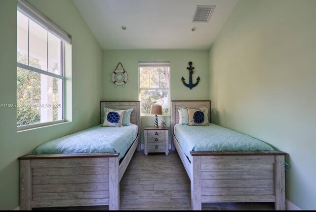 bedroom with wood finished floors and lofted ceiling