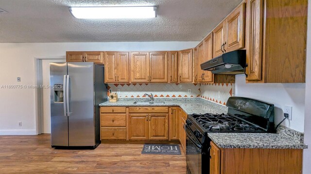 4878 Messana Ter, Lake Worth, FL 33463 - kitchen featuring stainless steel refrigerator with ice dispenser, under cabinet range hood, black range with gas stovetop, a sink, and light wood-type flooring
