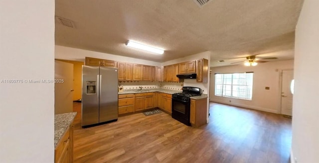 4878 Messana Ter, Lake Worth, FL 33463 - kitchen featuring stainless steel refrigerator with ice dispenser, black gas range, under cabinet range hood, light wood-style floors, and a textured ceiling
