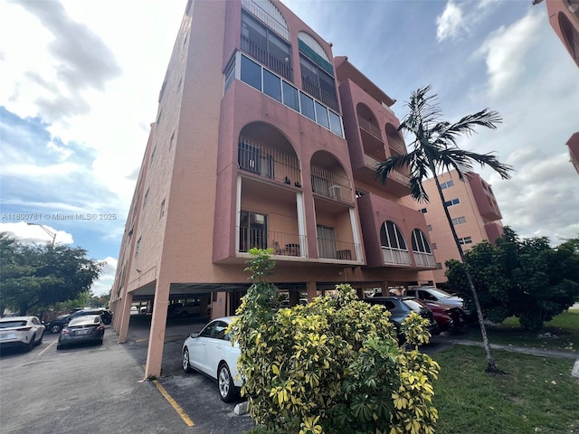 view of apartment building / complex with covered and uncovered parking