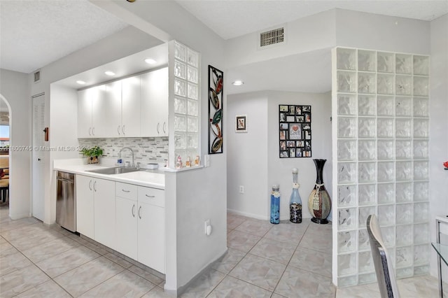 kitchen featuring a sink, dishwasher, light countertops, backsplash, and light tile patterned flooring