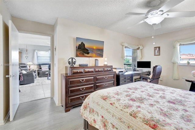 bedroom with light wood-type flooring, multiple windows, a textured ceiling, and ceiling fan