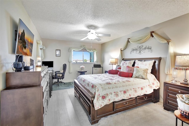 bedroom featuring a desk, a textured ceiling, ceiling fan, and light carpet