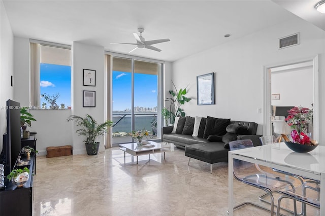 living room with a wall of windows, ceiling fan, and marble tiled flooring