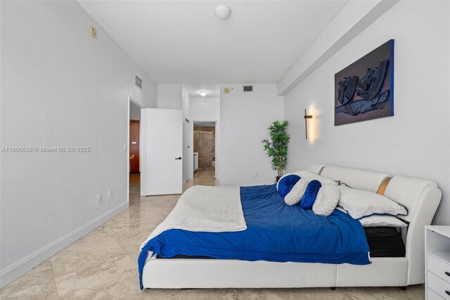 bedroom with marble look tile flooring, baseboards, and ensuite bath
