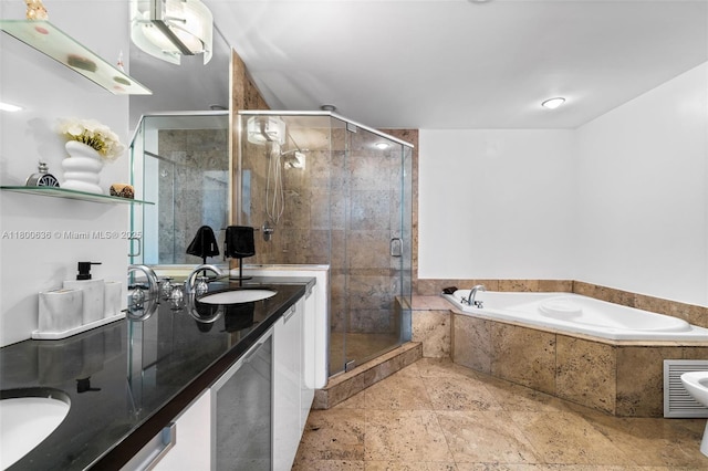 bathroom featuring double vanity, a garden tub, a stall shower, and stone tile flooring