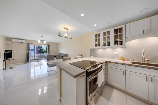 kitchen featuring stainless steel range with electric stovetop, a sink, light marble finish flooring, an AC wall unit, and white cabinetry
