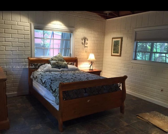 bedroom with baseboards and brick wall