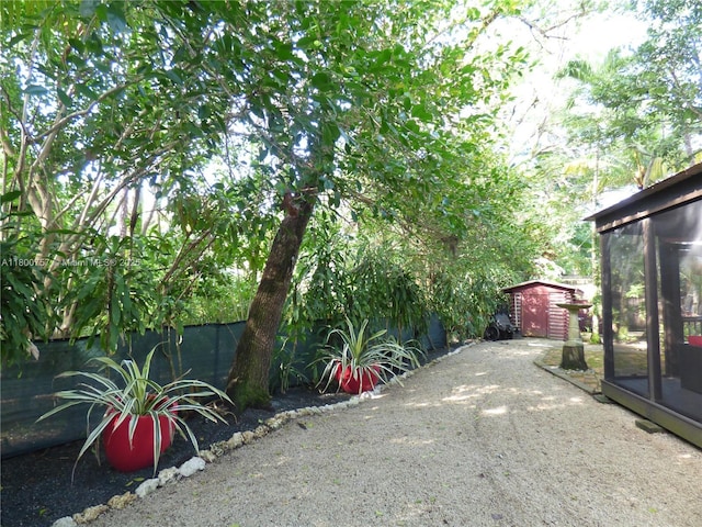 view of yard featuring a shed, an outdoor structure, fence, and a sunroom