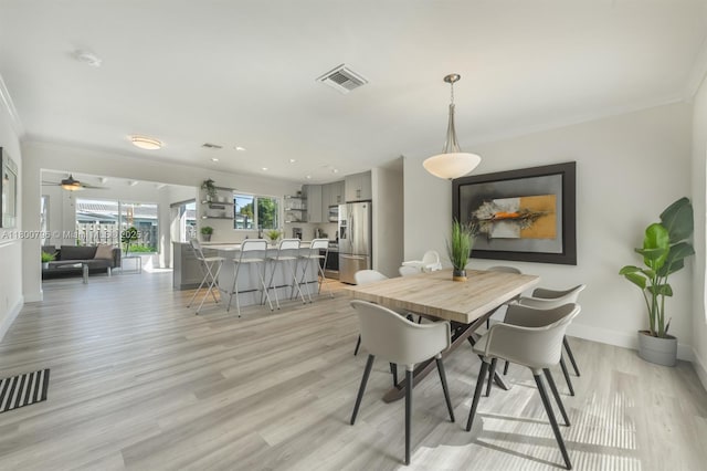 dining area featuring ornamental molding, light wood finished floors, baseboards, and ceiling fan